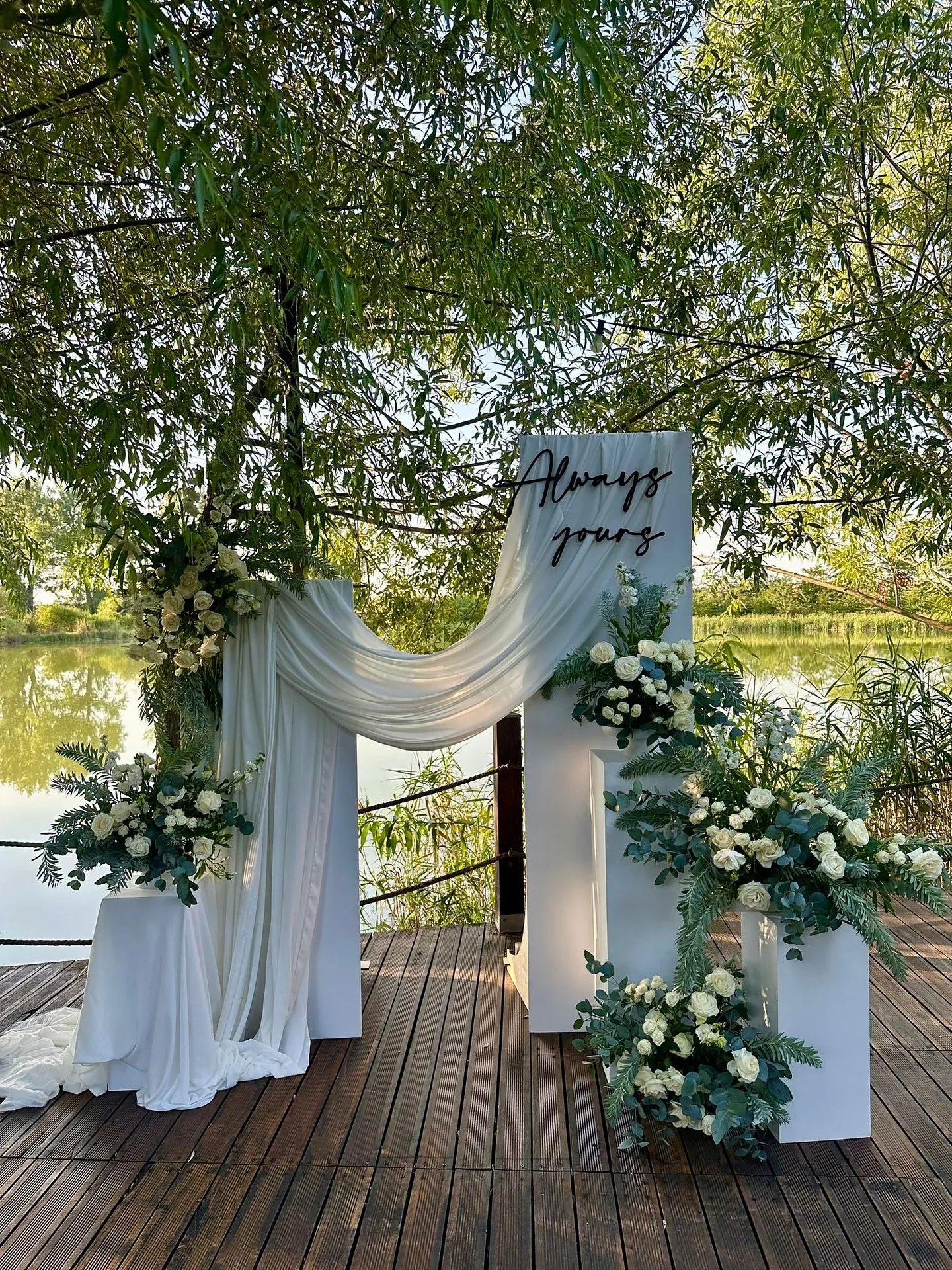 Decor de ceremonie lângă lac cu draperii albe